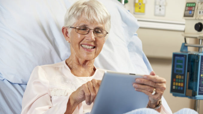 Patientin mit Tablet-PC im Krankenhausbett