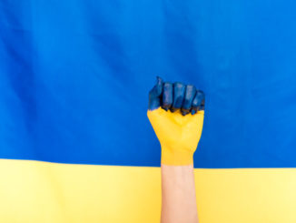 painted hand on Ukrainian flag background