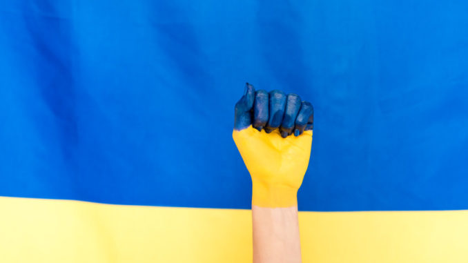 painted hand on Ukrainian flag background